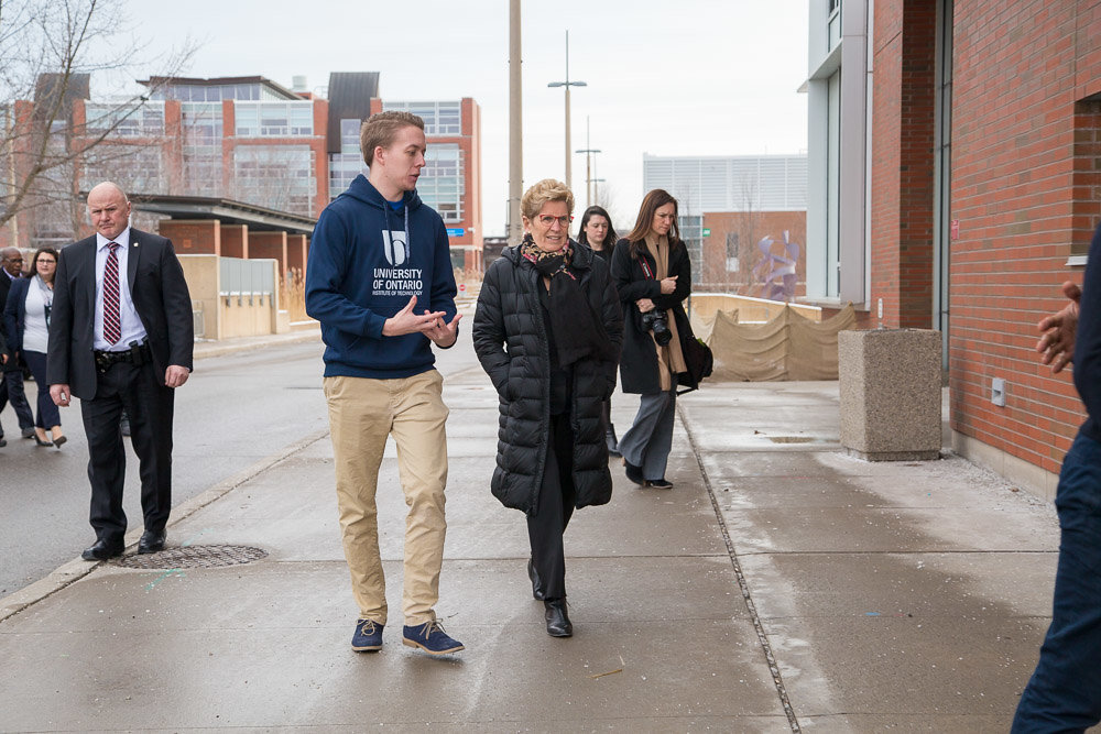 Premier Wynne walks between the Library and OPG Engineering Building toward the ACE facility.